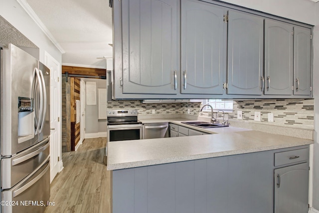 kitchen with gray cabinets, appliances with stainless steel finishes, ornamental molding, a sink, and a peninsula