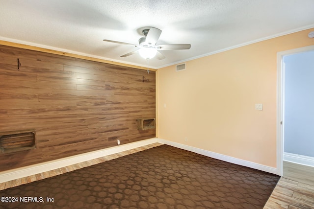 unfurnished room featuring crown molding, baseboards, visible vents, and wooden walls