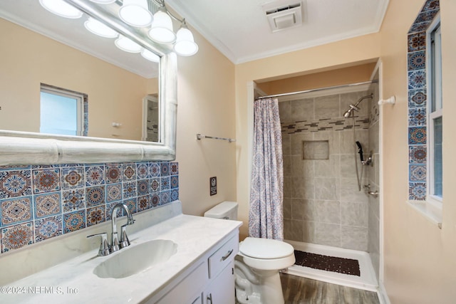 full bath featuring visible vents, toilet, ornamental molding, vanity, and tiled shower