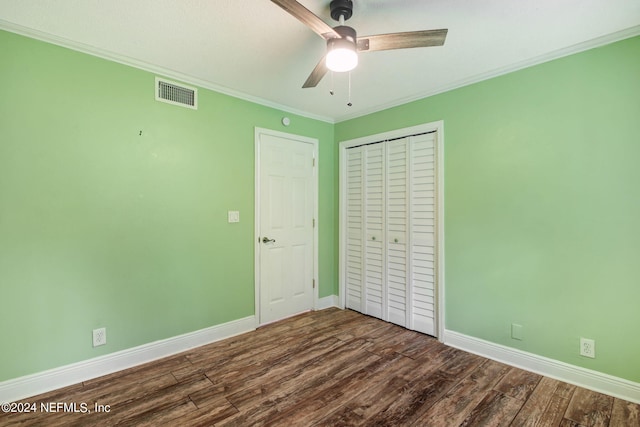 unfurnished bedroom featuring baseboards, visible vents, dark wood-style floors, crown molding, and a closet