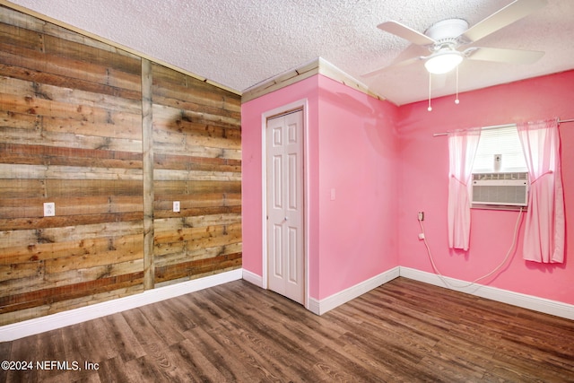 unfurnished room with baseboards, ceiling fan, wood finished floors, cooling unit, and a textured ceiling