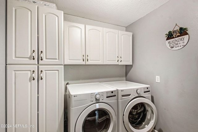 clothes washing area with a textured ceiling, washer and clothes dryer, and cabinet space