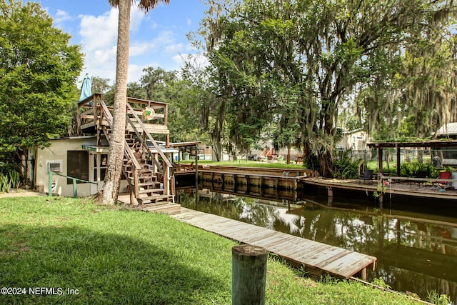 dock area featuring a water view, stairway, and a lawn