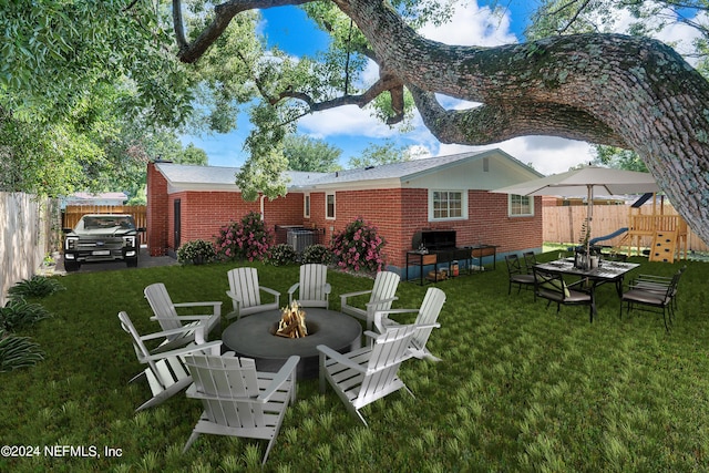 4435 Bedivere Rd, Jacksonville, FL 32208 - back of property with a playground, an outdoor fire pit, a fenced backyard, brick siding, and a lawn