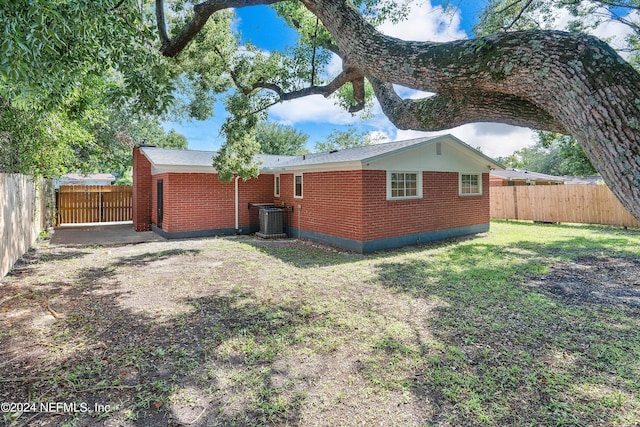 4435 Bedivere Rd, Jacksonville, FL 32208 - back of house with central AC, brick siding, a fenced backyard, and a lawn