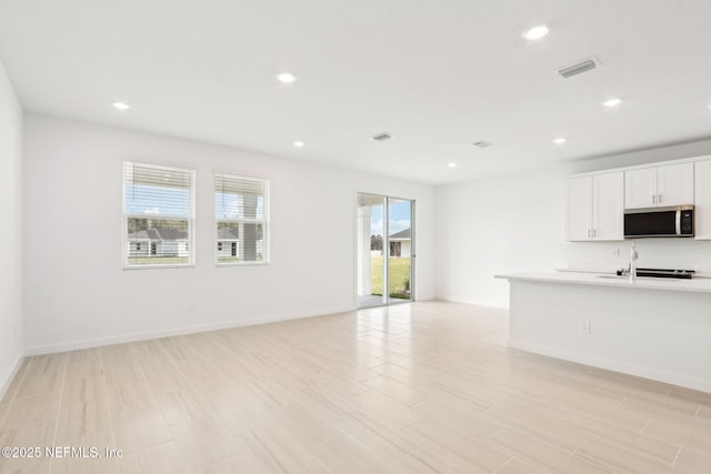 unfurnished living room with recessed lighting, visible vents, light wood-style flooring, and baseboards