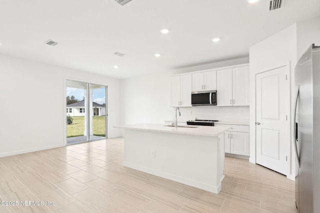 kitchen featuring visible vents, appliances with stainless steel finishes, white cabinets, and a sink