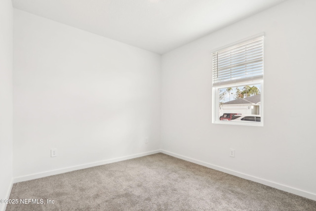 carpeted empty room featuring baseboards