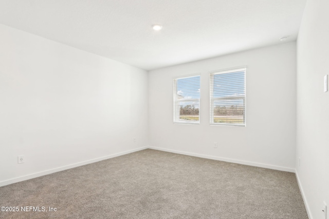 carpeted spare room featuring baseboards