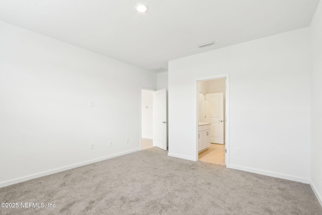 unfurnished bedroom with light colored carpet, visible vents, baseboards, and ensuite bathroom