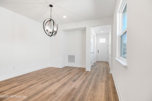 unfurnished dining area featuring a chandelier and light wood-type flooring