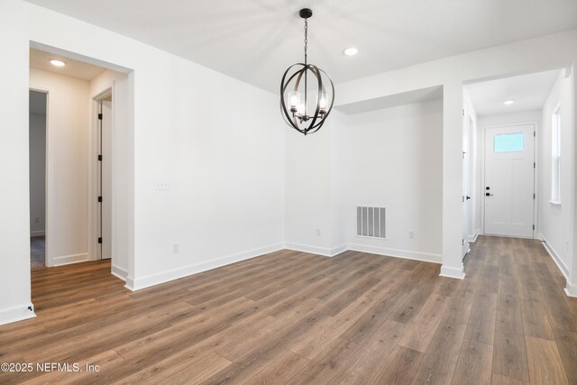 unfurnished dining area featuring a notable chandelier and dark hardwood / wood-style floors