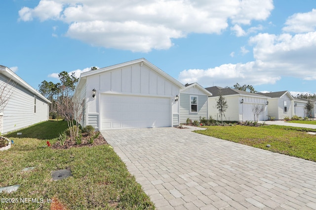 ranch-style home with board and batten siding, decorative driveway, an attached garage, and a front lawn