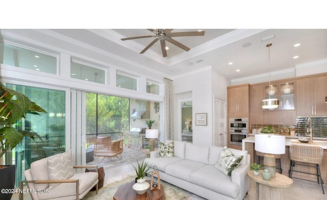 living room with crown molding, a towering ceiling, ceiling fan, and sink