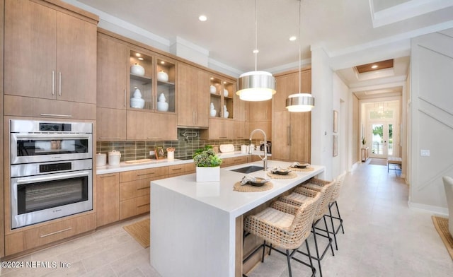 kitchen featuring double oven, decorative light fixtures, sink, a kitchen bar, and crown molding