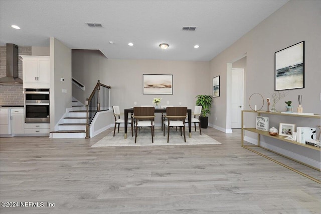 dining area with a textured ceiling and light wood-type flooring