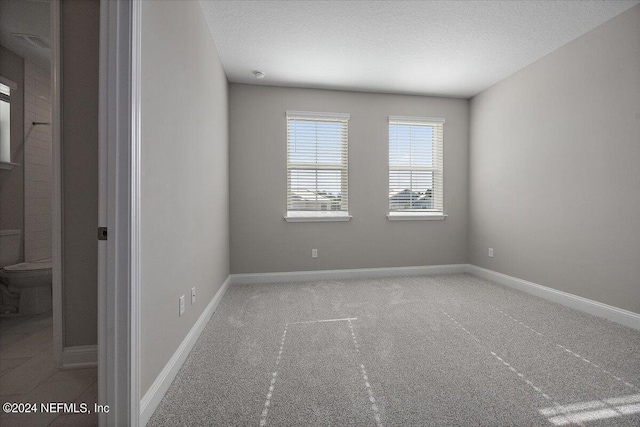 unfurnished room with a textured ceiling and carpet