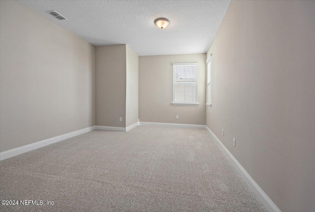 carpeted spare room with a textured ceiling