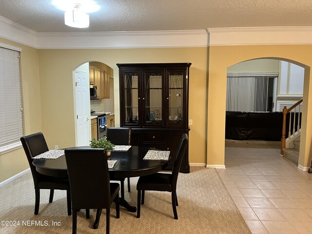 dining area featuring light tile patterned floors, arched walkways, ornamental molding, stairs, and a textured ceiling