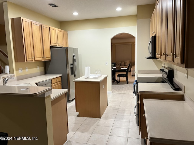 kitchen with visible vents, arched walkways, a kitchen island, appliances with stainless steel finishes, and a sink