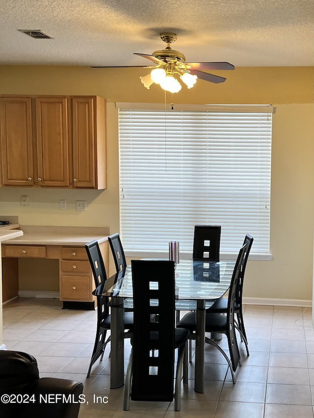dining area featuring light tile patterned floors, built in desk, a textured ceiling, and visible vents