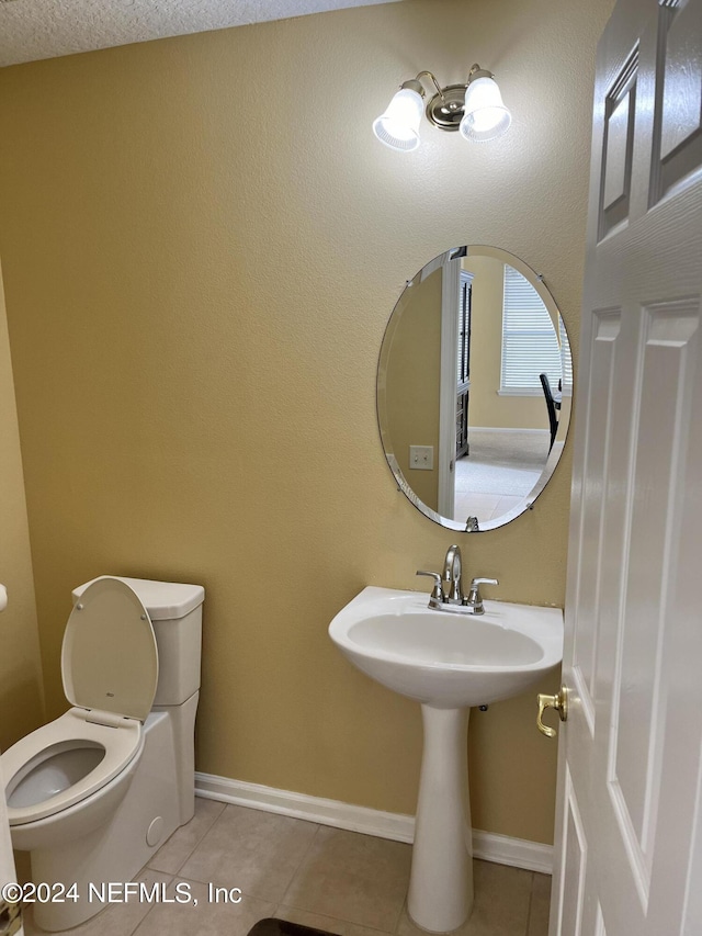 half bathroom with tile patterned flooring, baseboards, and toilet