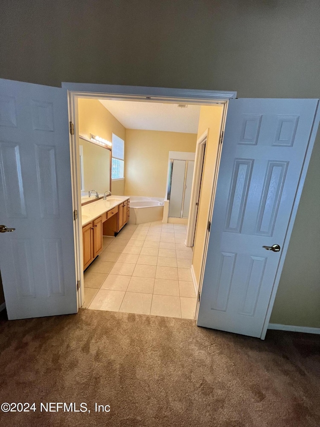 bathroom with carpet, tile patterned flooring, a bath, and vanity