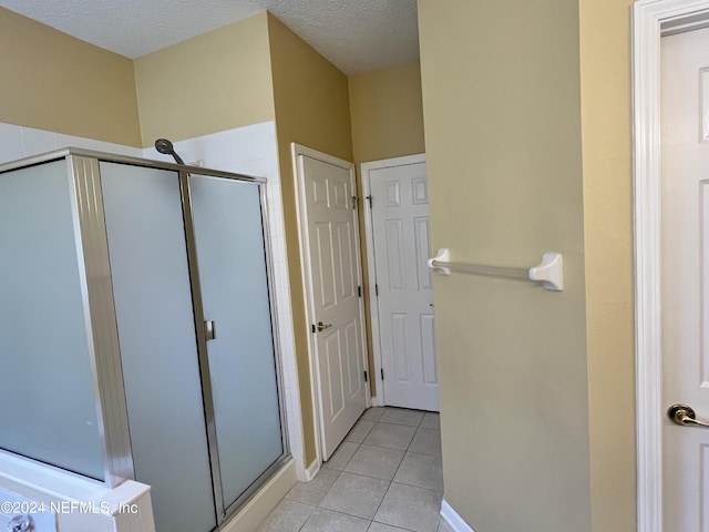 full bathroom with a textured ceiling, a stall shower, and tile patterned flooring