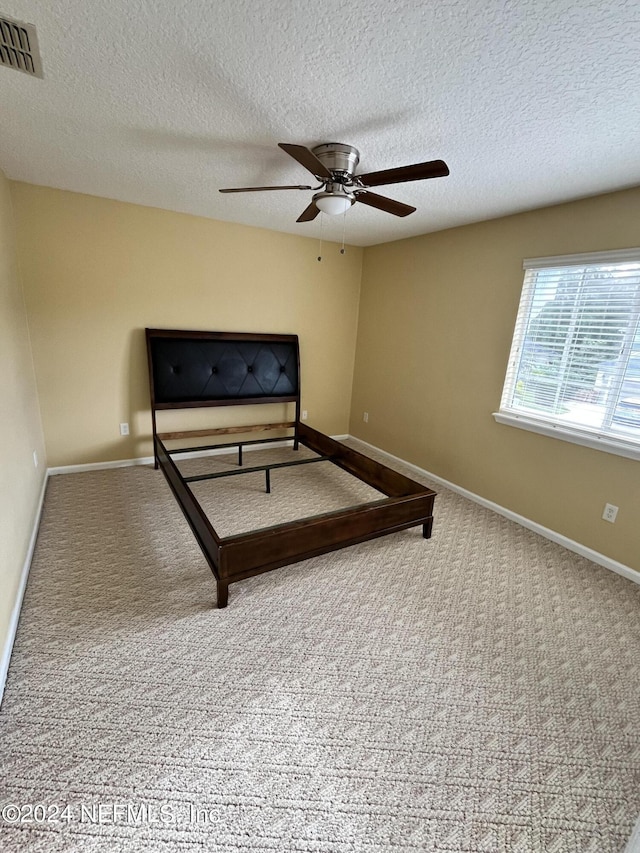 bedroom with carpet, a textured ceiling, visible vents, and baseboards