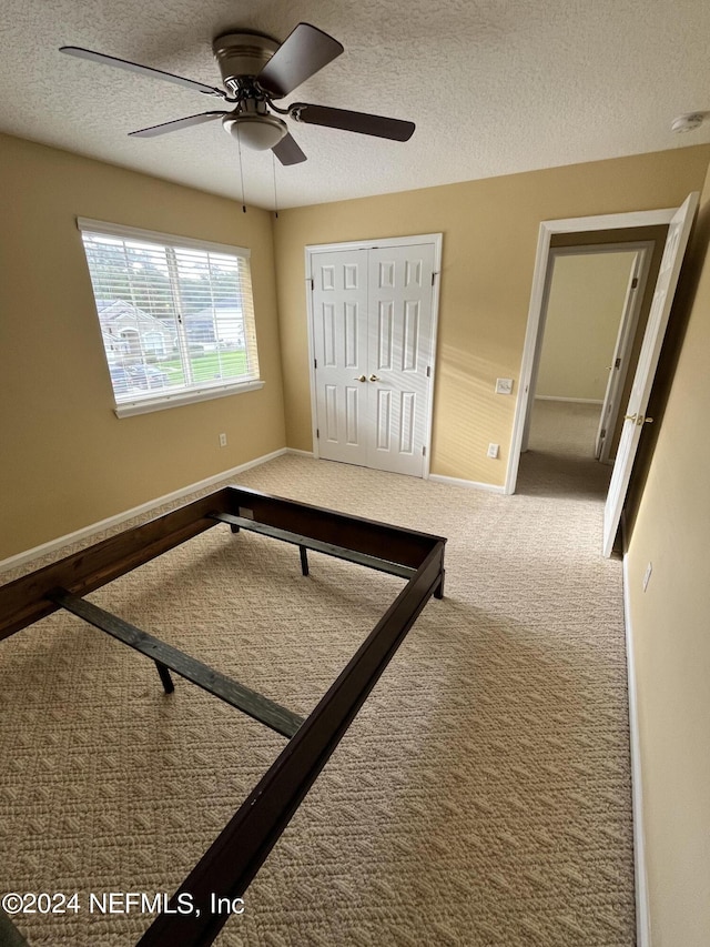 unfurnished bedroom with a closet, carpet flooring, a textured ceiling, and baseboards