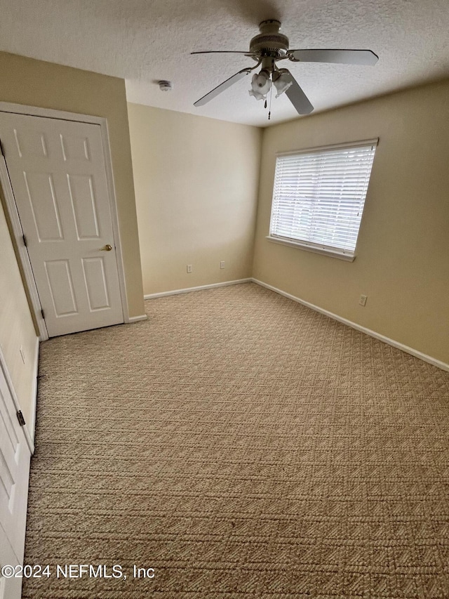 unfurnished bedroom featuring carpet, baseboards, ceiling fan, and a textured ceiling