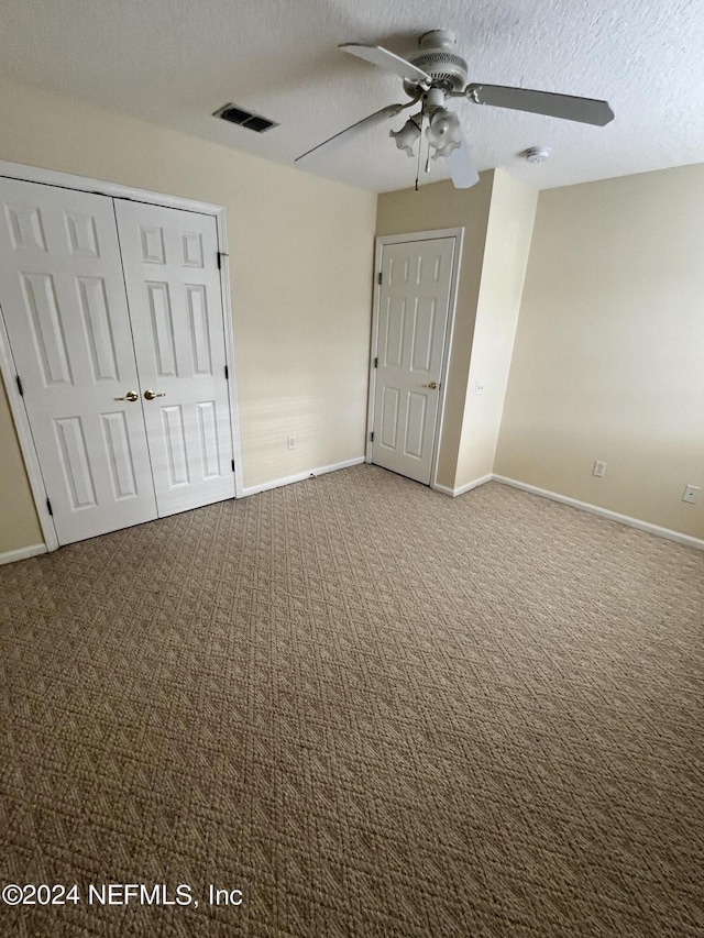 unfurnished bedroom featuring carpet, a closet, visible vents, a textured ceiling, and baseboards