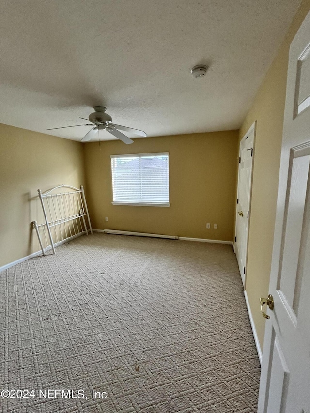 unfurnished room featuring a textured ceiling, carpet flooring, a ceiling fan, and baseboards