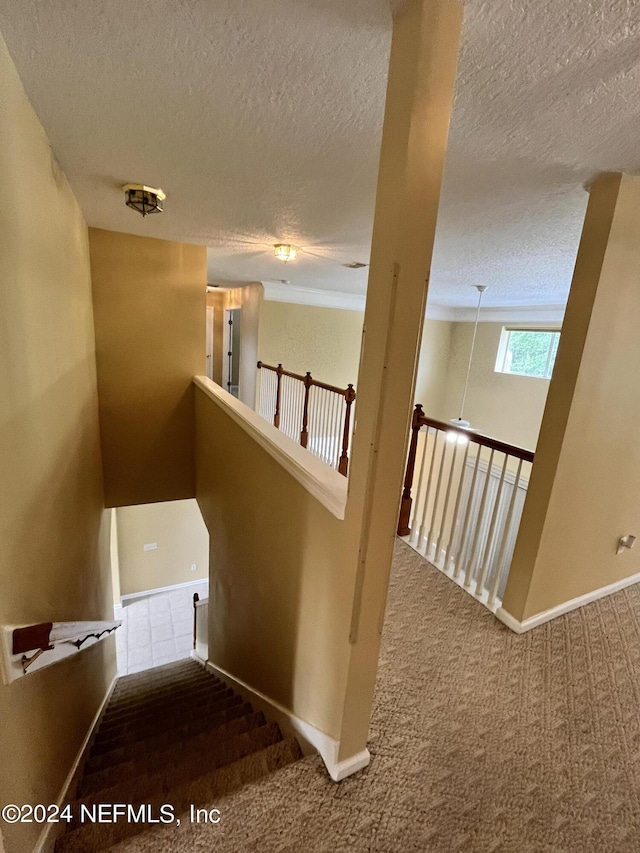 stairway featuring carpet floors, a textured ceiling, and baseboards
