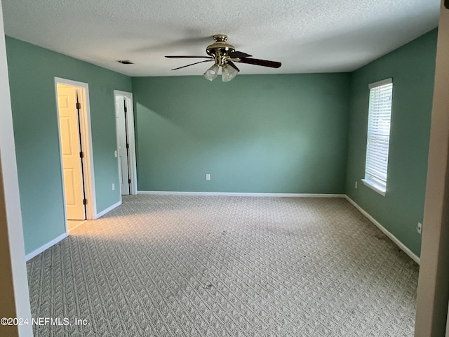 empty room featuring a textured ceiling, visible vents, a ceiling fan, baseboards, and carpet