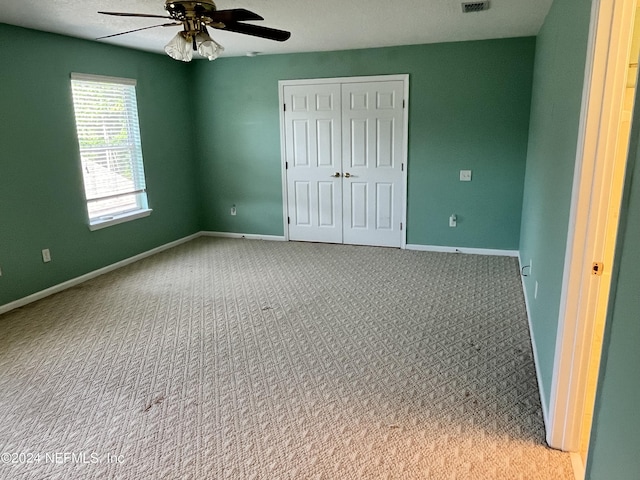 unfurnished bedroom featuring visible vents, baseboards, ceiling fan, carpet, and a closet