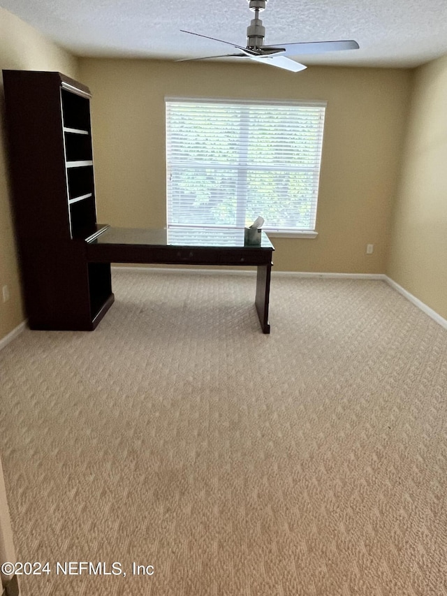 unfurnished office with carpet, ceiling fan, a textured ceiling, and baseboards