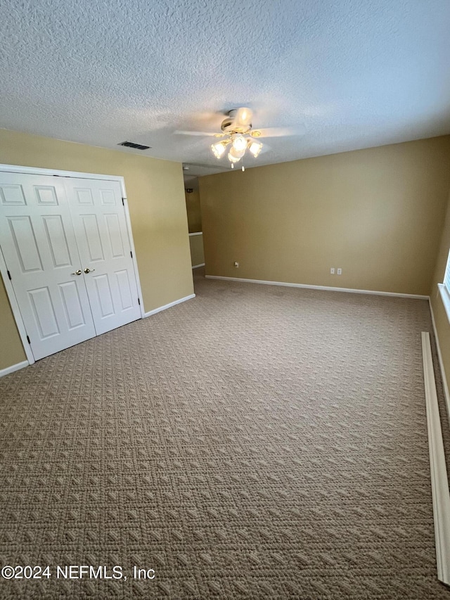 unfurnished bedroom featuring carpet, a closet, visible vents, a textured ceiling, and baseboards