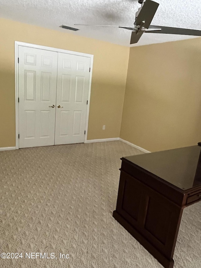 unfurnished bedroom with a textured ceiling, carpet, a ceiling fan, and baseboards