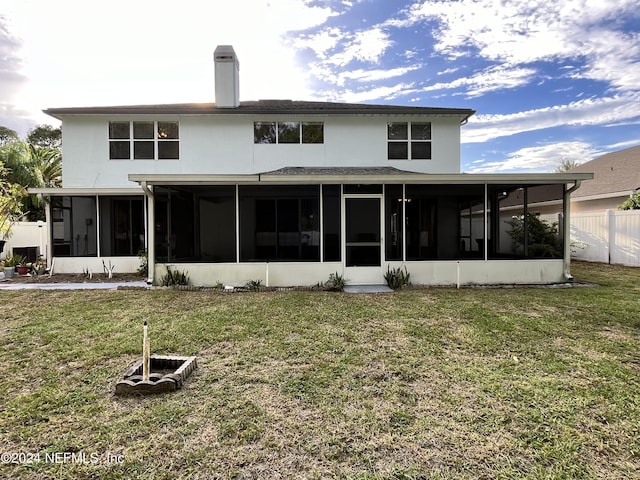 back of property featuring a yard, a chimney, stucco siding, a sunroom, and fence