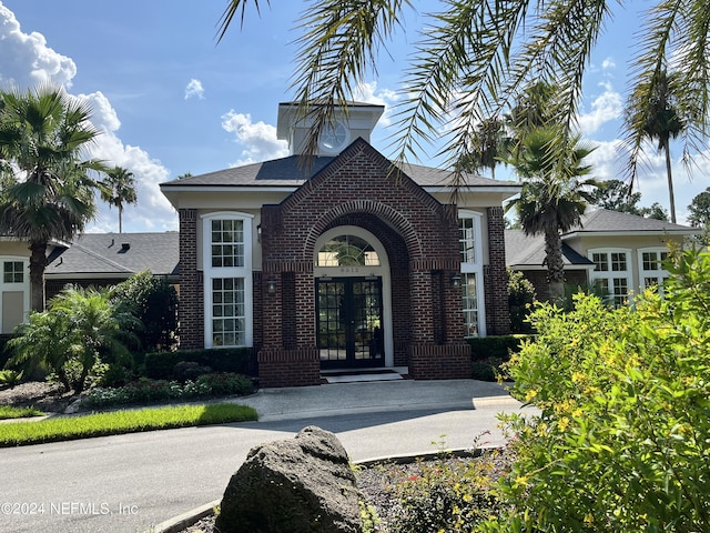 property entrance with a shingled roof, french doors, and brick siding