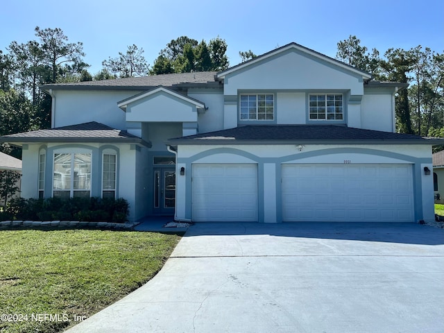 view of property featuring a garage and a front lawn