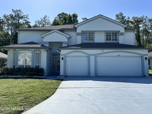 traditional-style home with concrete driveway, a front lawn, an attached garage, and stucco siding