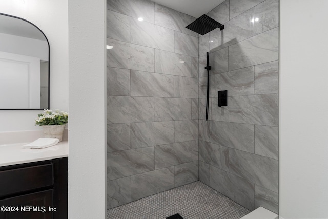 bathroom with tiled shower and vanity