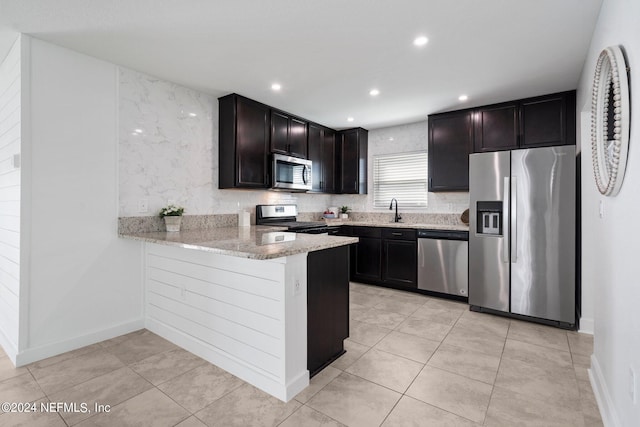 kitchen featuring appliances with stainless steel finishes, light tile patterned floors, kitchen peninsula, and light stone countertops