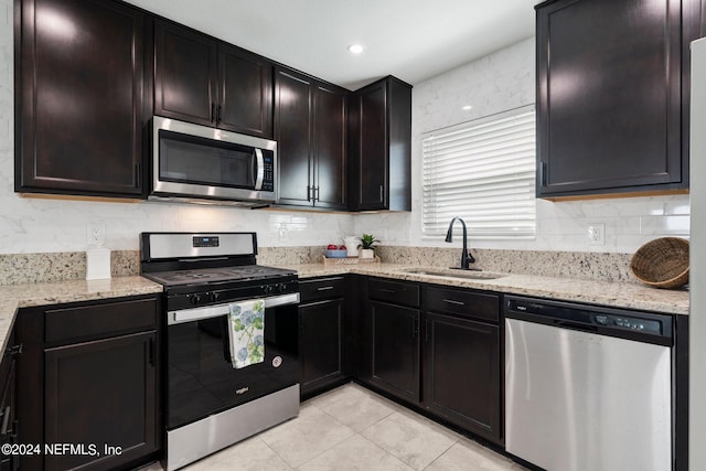 kitchen with light tile patterned floors, appliances with stainless steel finishes, sink, and light stone counters