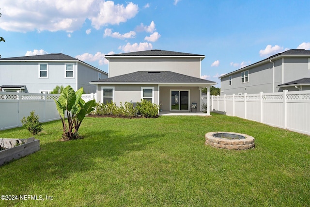 rear view of property featuring a lawn and an outdoor fire pit