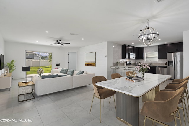 dining space featuring ceiling fan with notable chandelier, light tile patterned floors, and sink