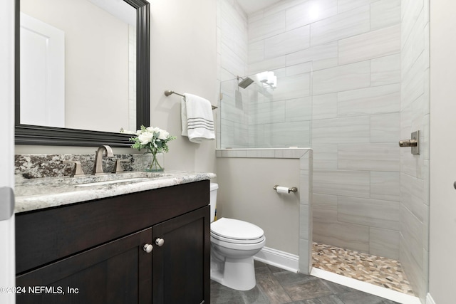 bathroom with vanity, toilet, and a tile shower