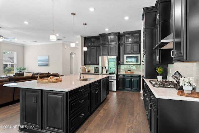 kitchen with sink, hanging light fixtures, ornamental molding, appliances with stainless steel finishes, and a kitchen island with sink